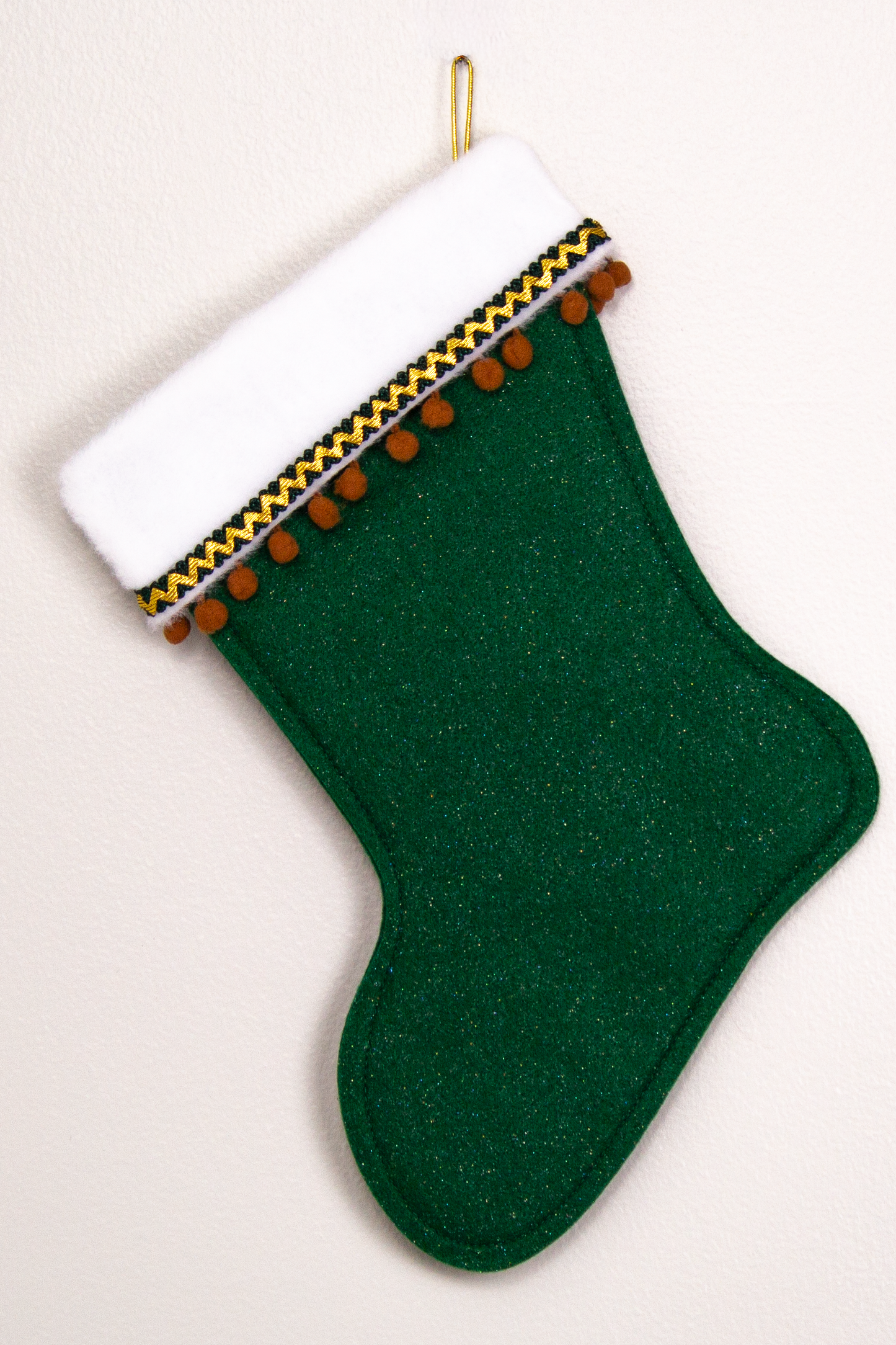 Dark green glitter felt handmade Christmas stocking with pom poms and decorated in brown & gold. (back of Sasquatch Santa stocking)