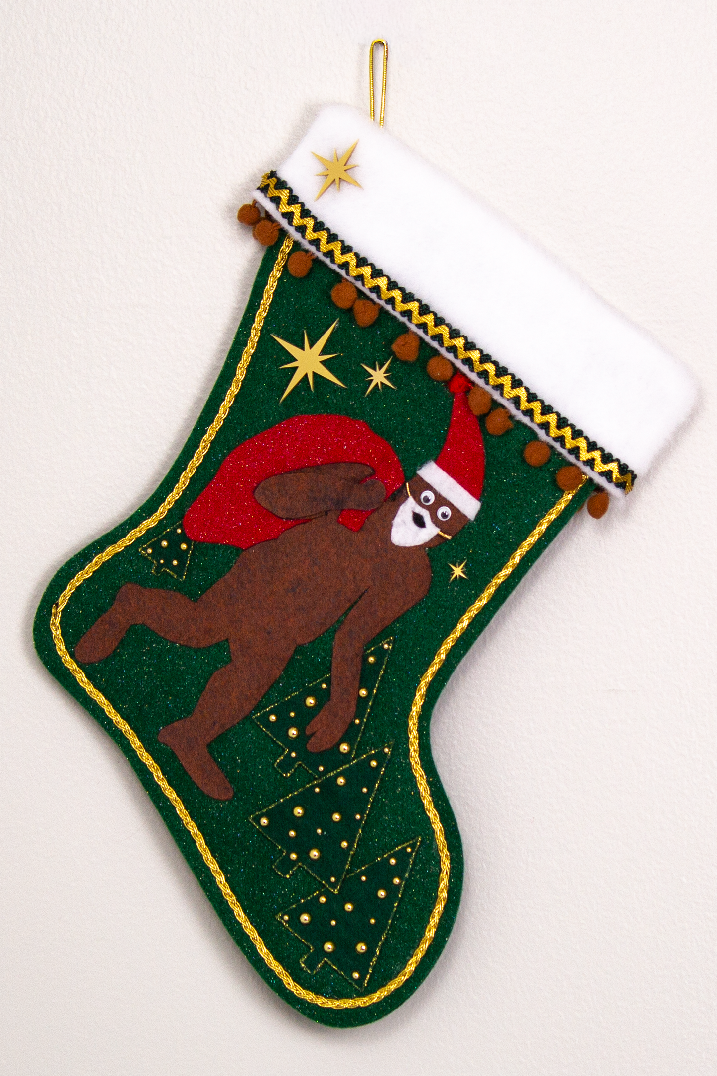 Felt Sasquatch Santa, red glitter bag/hat on dark green glitter felt handmade Christmas stocking with pom poms, trees, acrylic starbursts and decorated in brown, red & gold. (front of stocking)