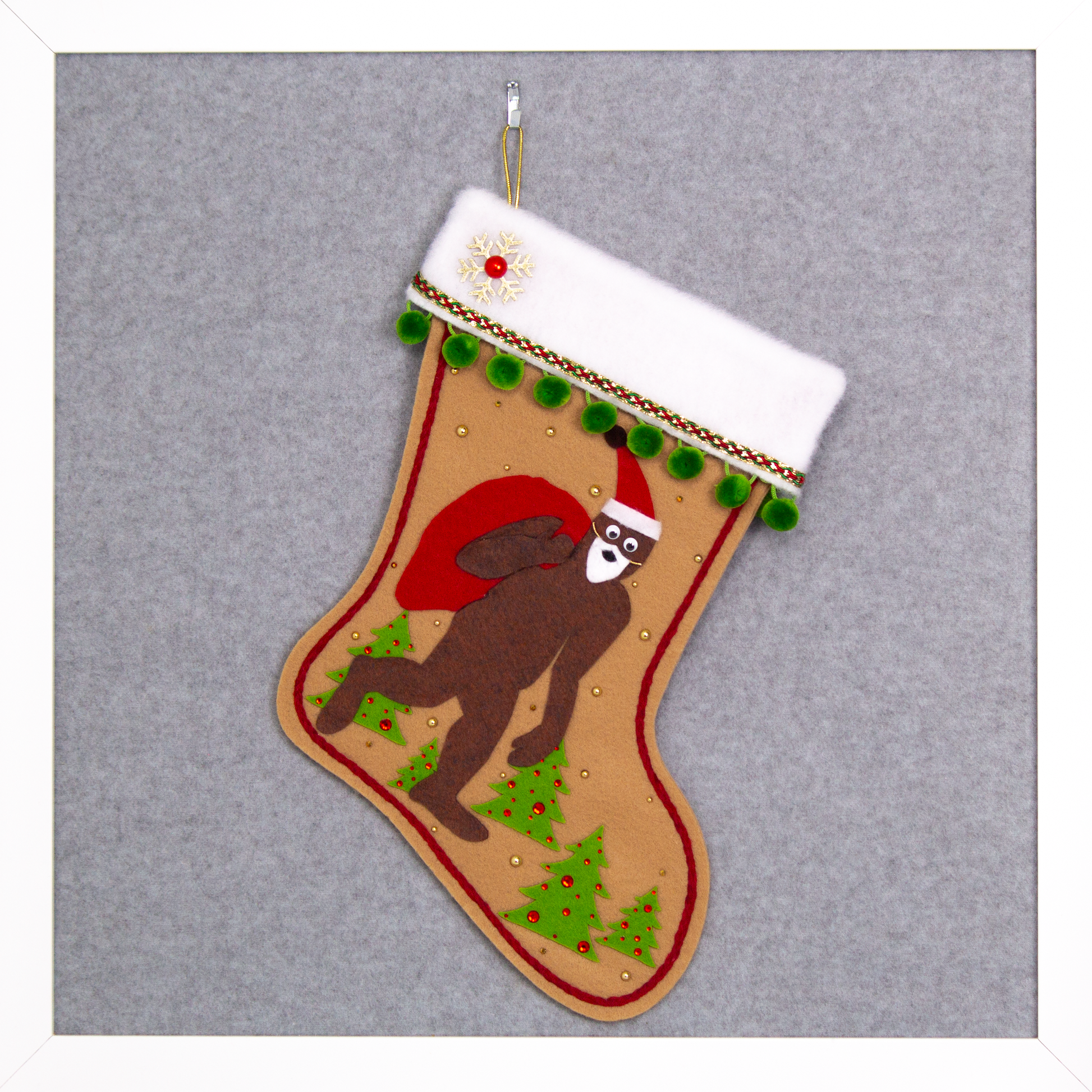 Felt Sasquatch Santa, red bag & hat on tan felt handmade Christmas stocking with pom poms, trees, a glittered snowflake button and decorated in green, red & gold. (front of stocking)