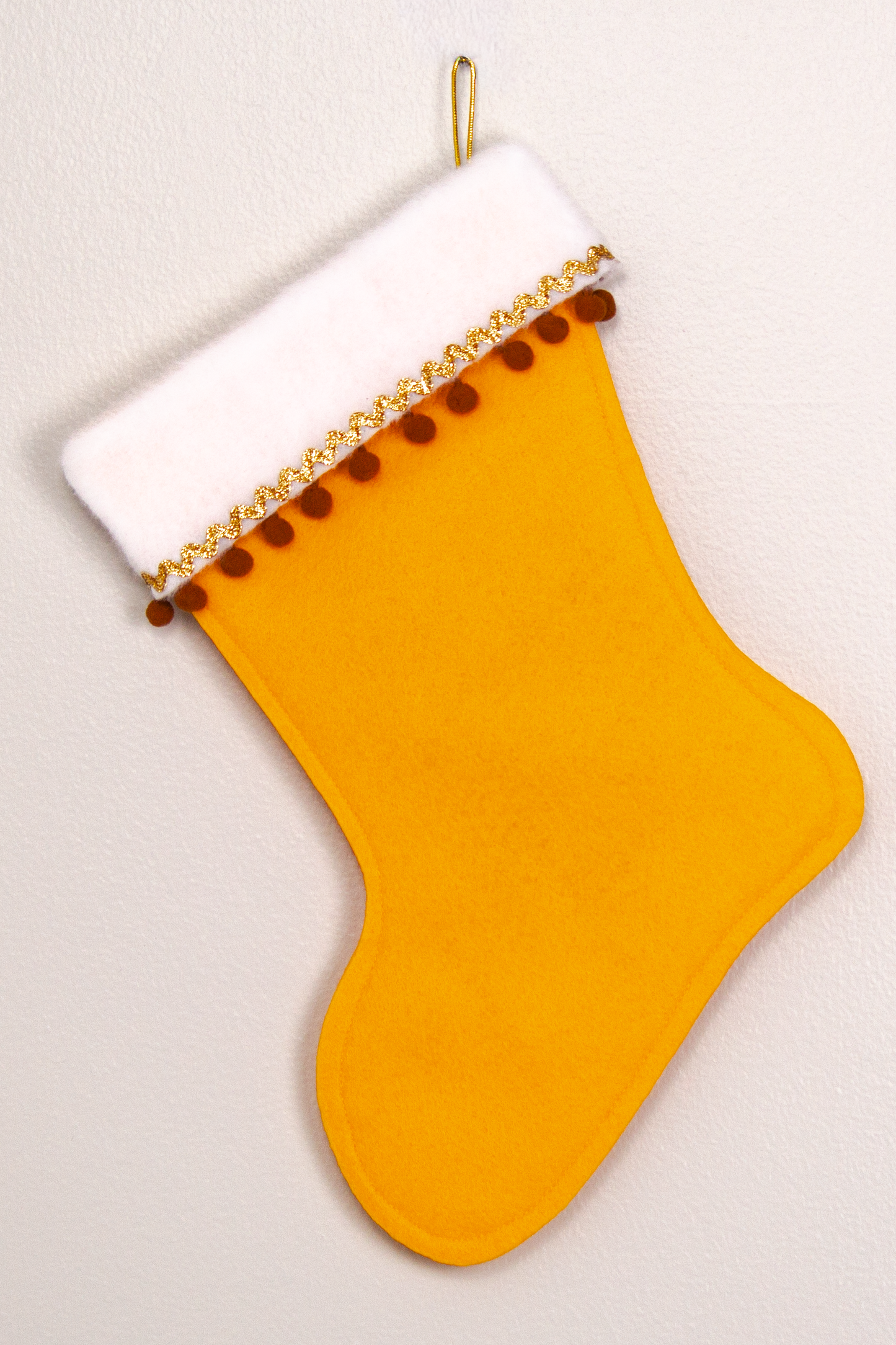 Golden felt handmade Christmas stocking with pom poms and decorated  in brown & gold. (back of Sasquatch Santa stocking)