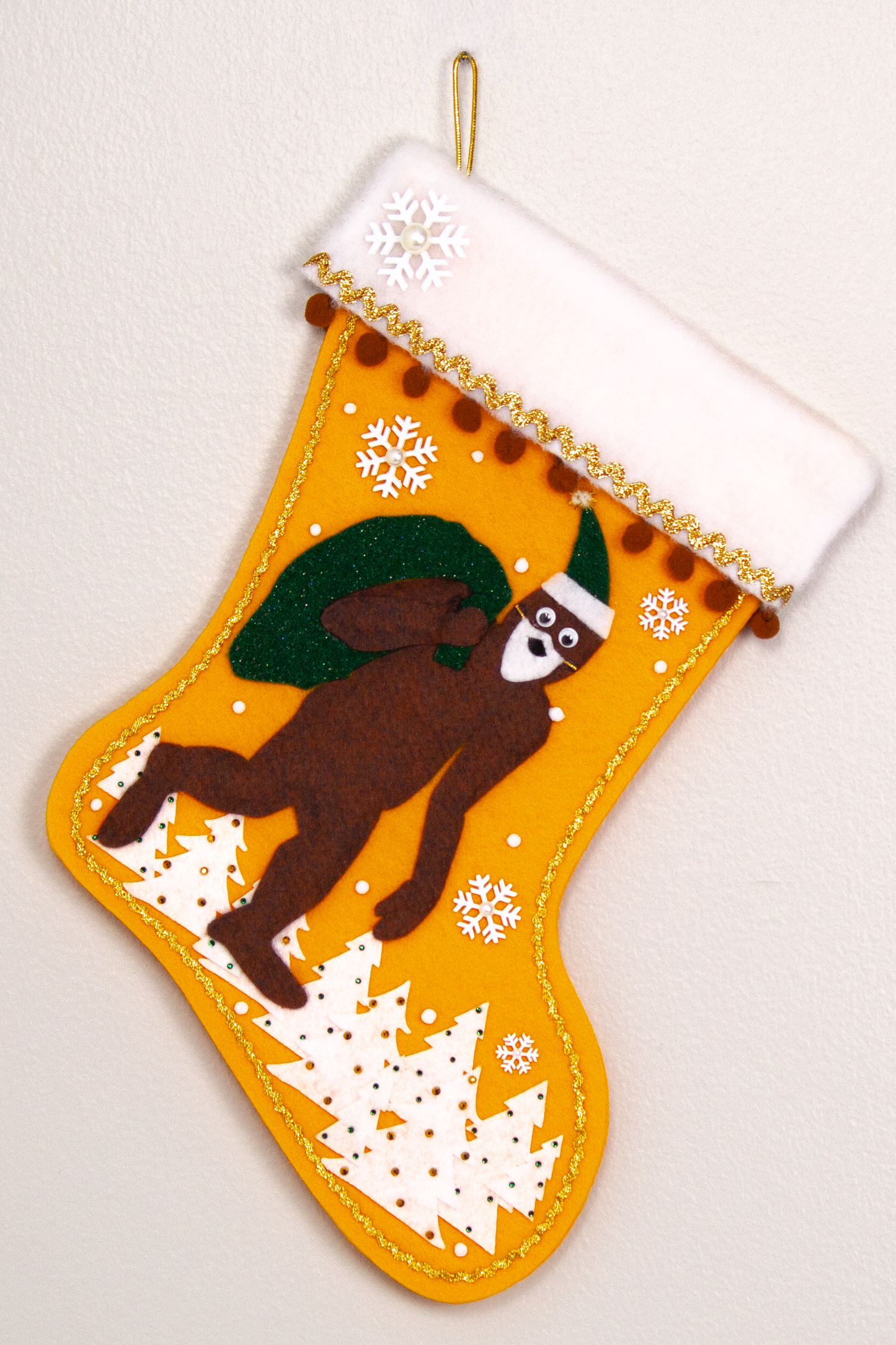 Felt Sasquatch Santa, dark green glitter bag/hat on golden felt handmade Christmas stocking with pom poms, trees and snowflake buttons decorated in white, brown & gold. (front of stocking)
