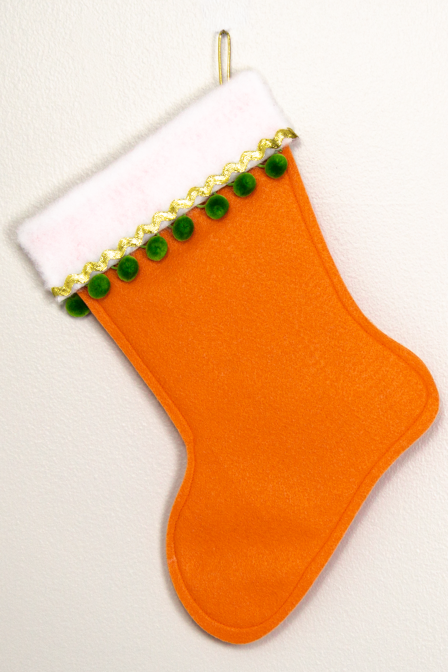 Orange felt handmade Christmas stocking with pom poms and decorated in gold & green. (back of Scottie dog stocking)