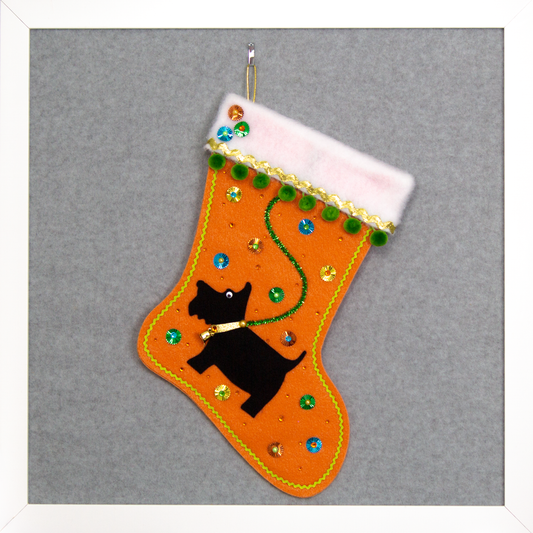 Black Scottish Terrier dog on orange felt handmade Christmas stocking with sunburst sequins, pom poms and decorated in gold, green, blue & orange. (front of stocking)