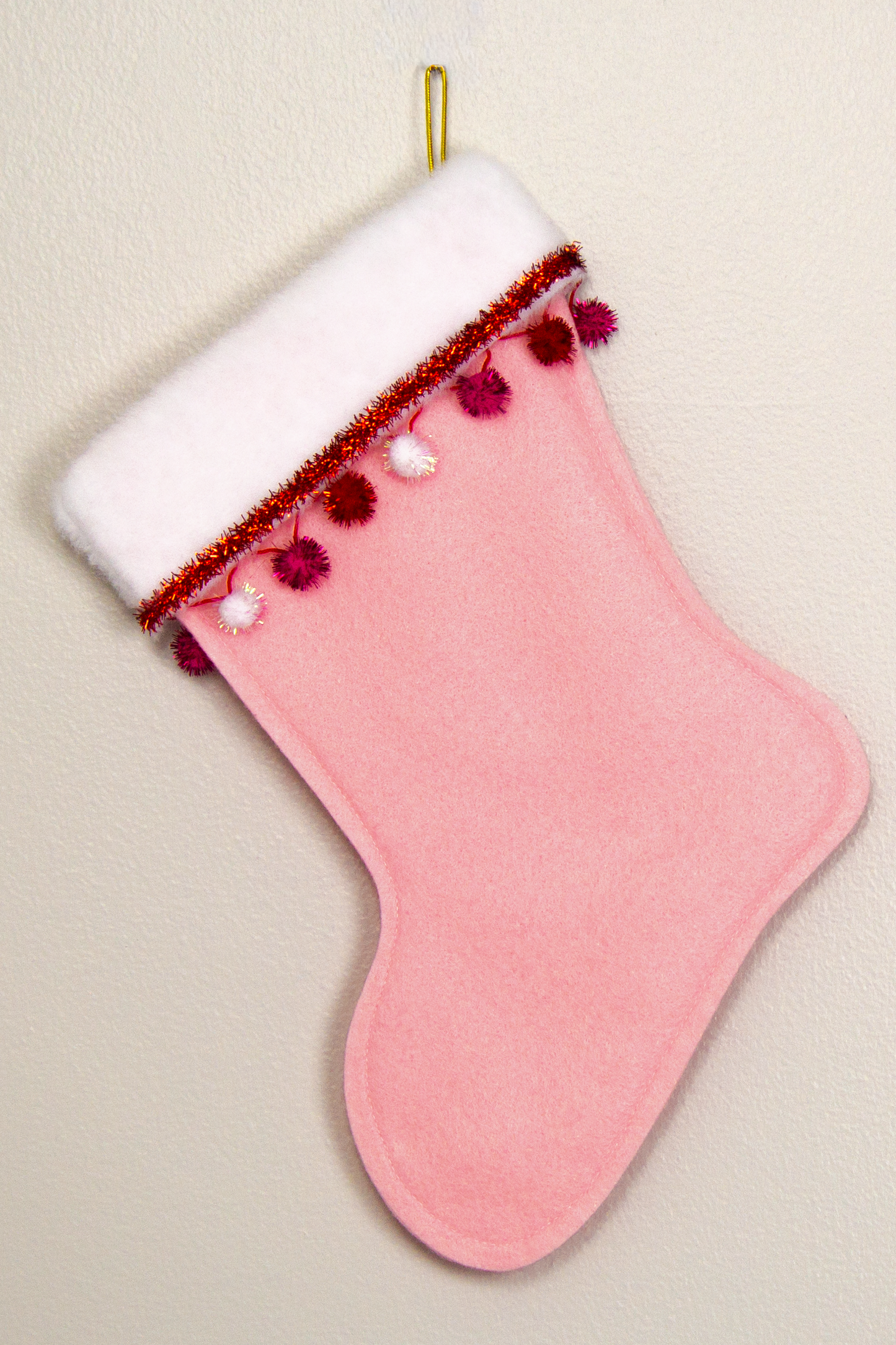 Light pink felt handmade Christmas stocking with sparkly pom poms, tinsel and decorated in red, pinks, white and gold. (back of Shih Tzu dog stocking)
