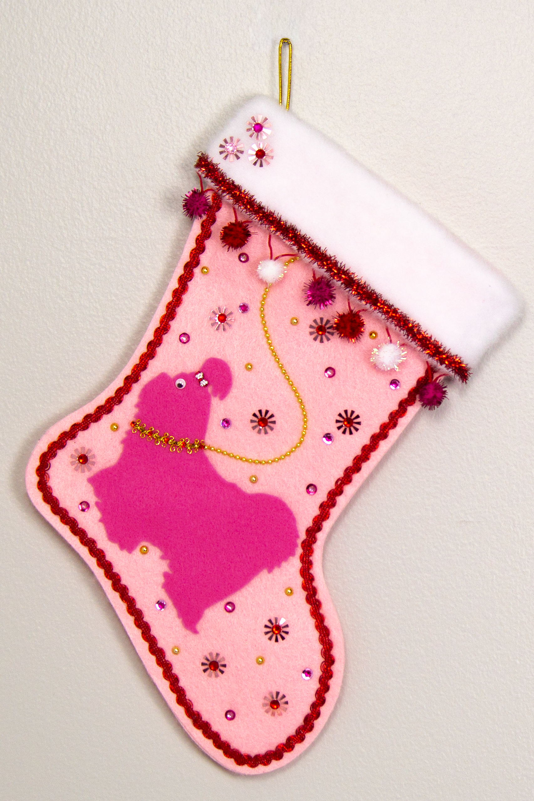 Candy pink Shih Tzu dog on light pink felt handmade Christmas stocking with sparkly pom poms, flower sequins, tinsel and decorated in red, pinks, white and gold. (front of stocking)