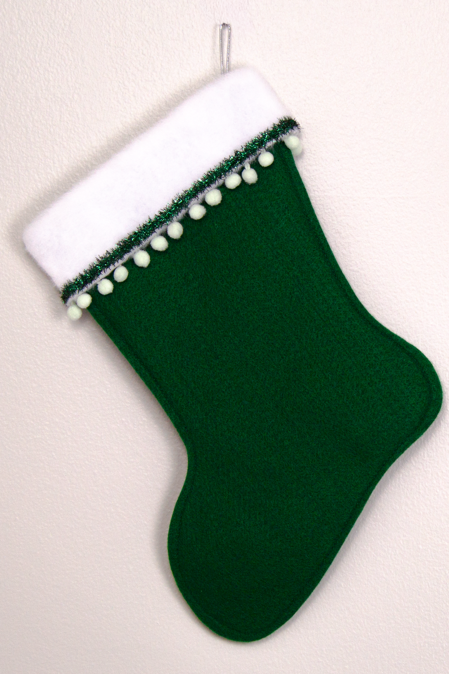 Dark green felt handmade Christmas stocking with pom poms, tinsel ribbon and decorations in mint green, silver and green. (back of Shih Tzu dog stocking)
