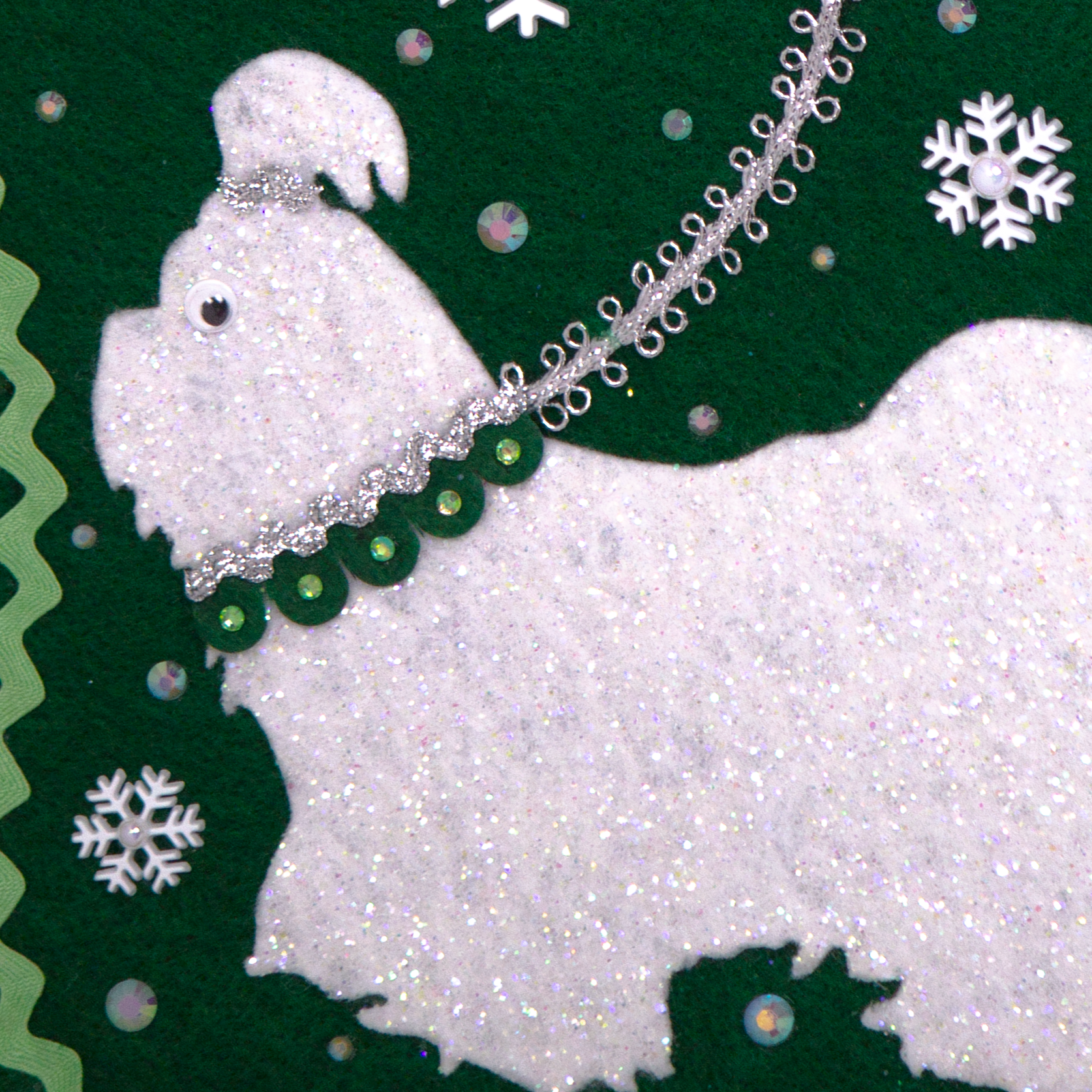 Detail of glittered white Shih Tzu dog on dark green felt handmade Christmas stocking with pom poms, snowflake buttons, tinsel ribbon and decorations in white, mint green, silver, green and clear. (front of stocking)