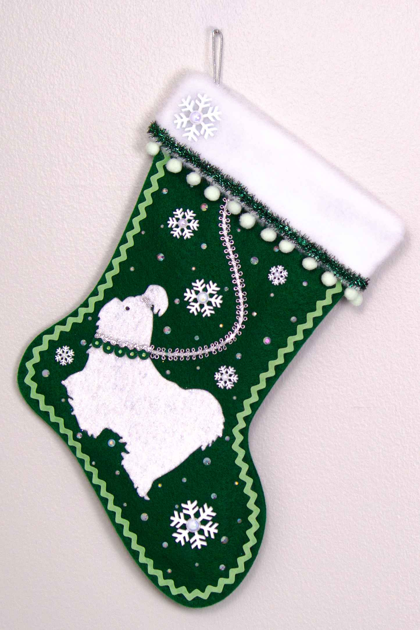 Glittered white Shih Tzu dog on dark green felt handmade Christmas stocking with pom poms, snowflake buttons, tinsel ribbon and decorations in white, mint green, silver, green and clear. (front of stocking)