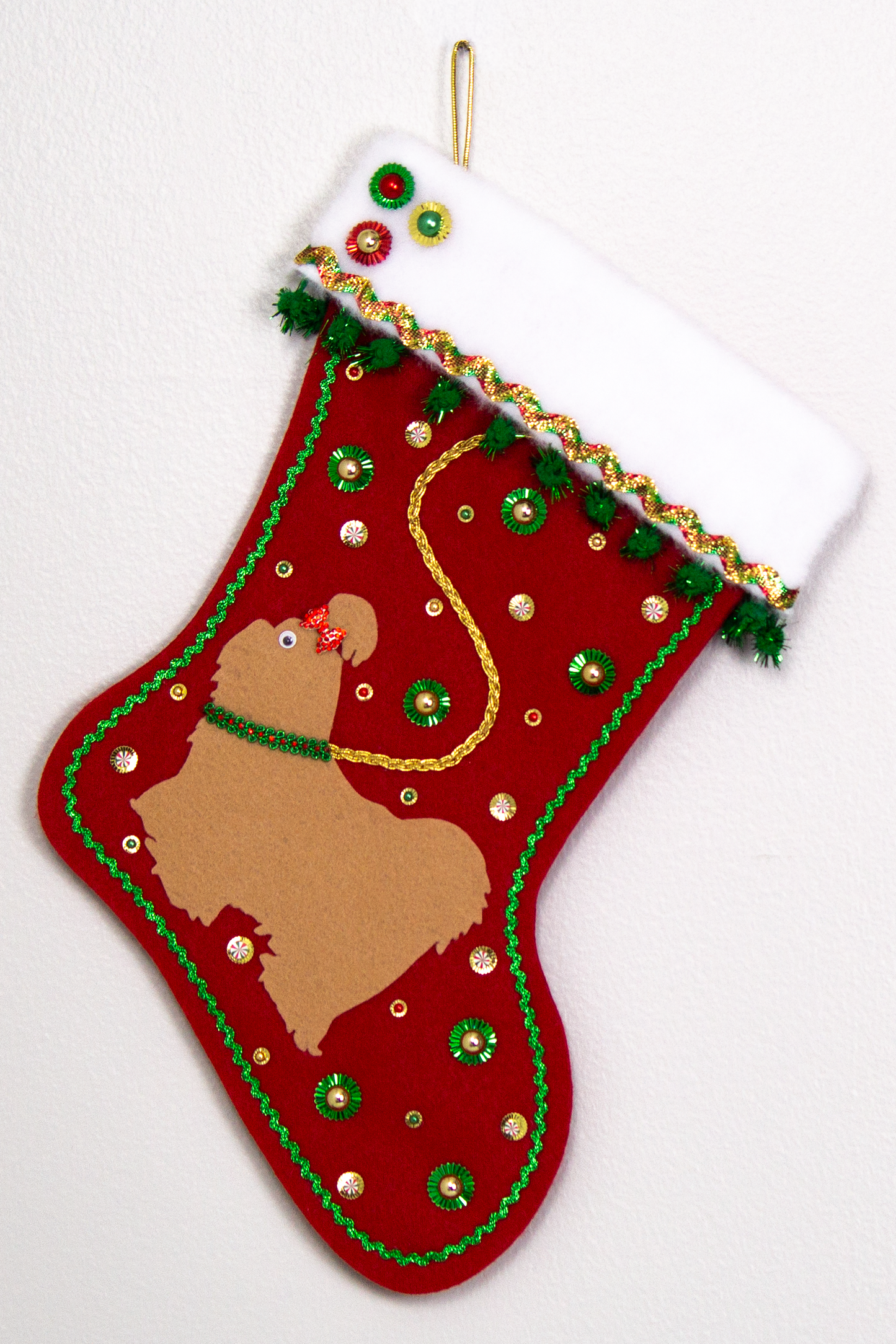 Tan Shih Tzu dog on holiday red felt handmade Christmas stocking with sunburst sequins, sparkly pom poms, metallic trim and decorations in red, green & gold. (front of stocking)
