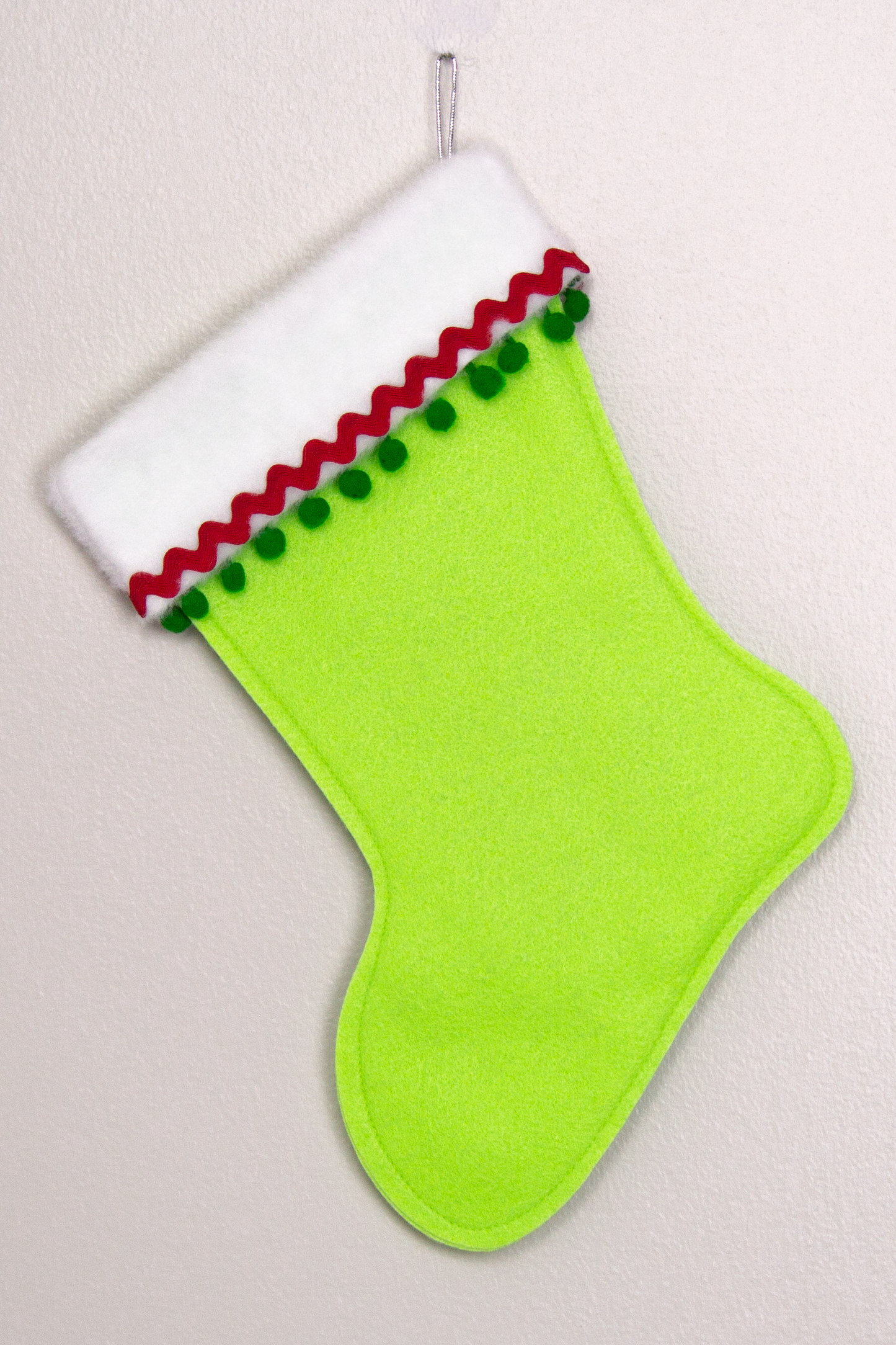 Neon green felt handmade Christmas stocking with pom poms and decorations in red, green & silver. (back of T-Rex stocking)