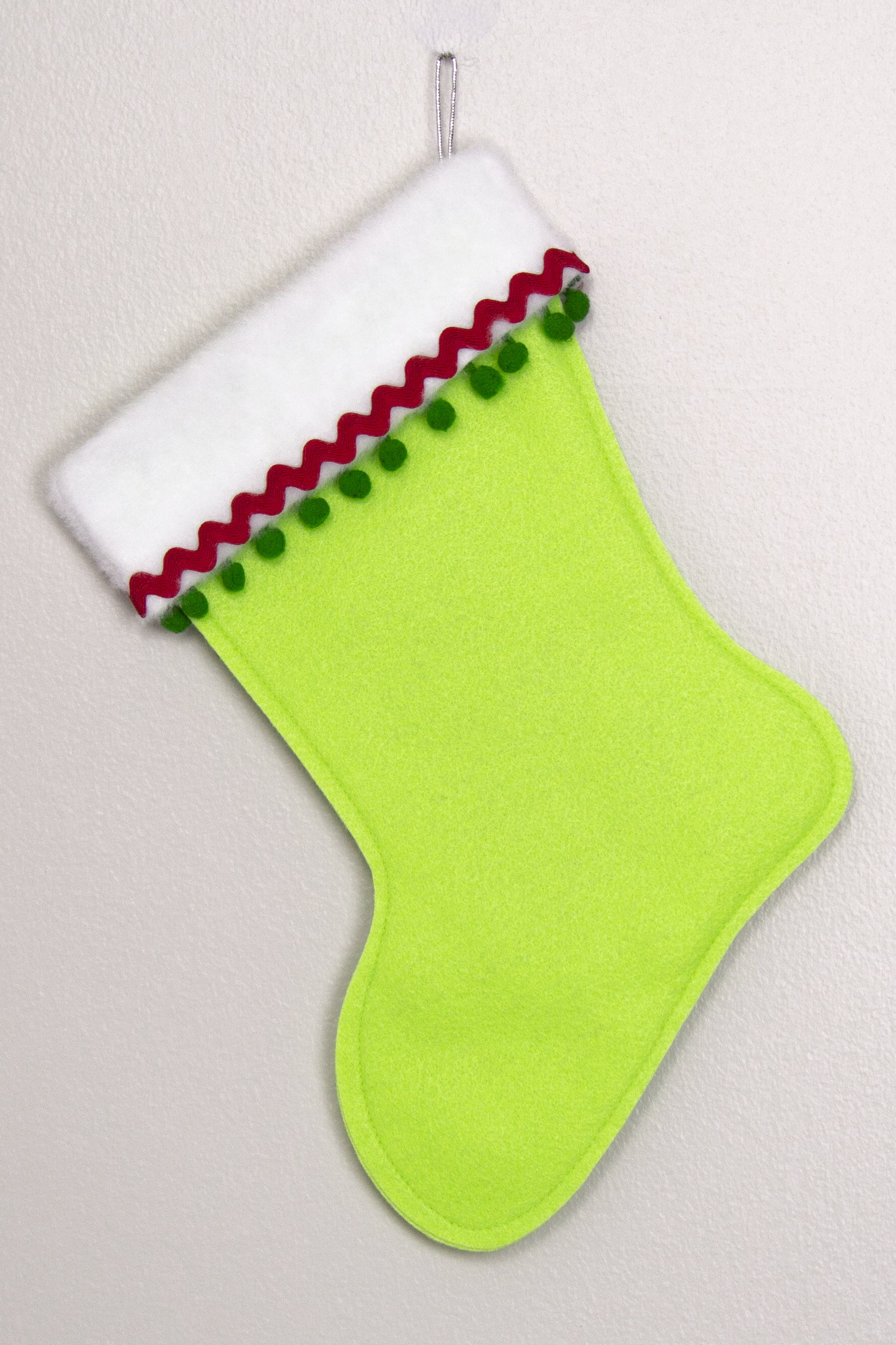 Neon green felt handmade Christmas stocking with pom poms and decorations in red, green & silver. (back of T-Rex stocking)