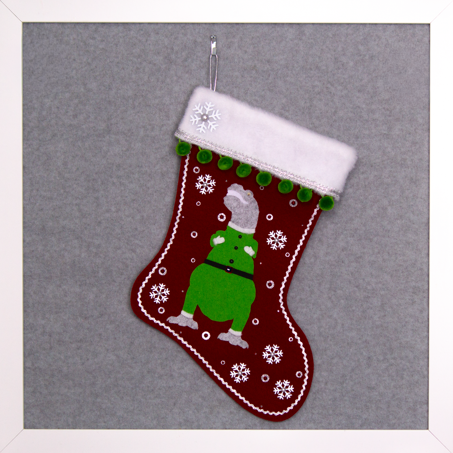 Variegated gray felt T-Rex with green suit on ruby red felt handmade Christmas stocking with pom poms,  snowflake buttons and decoration in white, ruby, green & silver. (front of stocking)