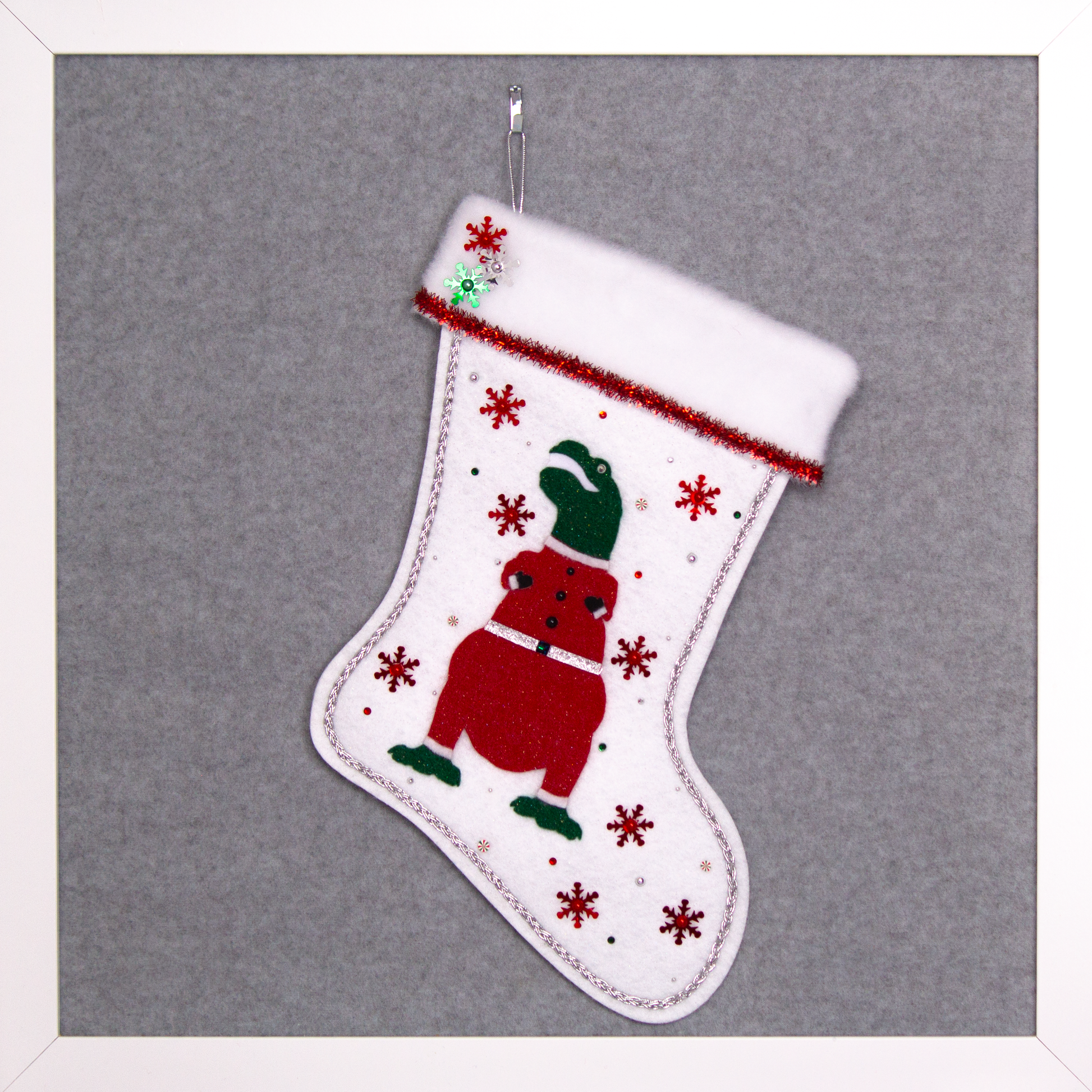 Dark green glitter felt T-Rex with red glitter suit on white glitter felt handmade Christmas stocking with tinsel ribbon, snowflake sequins and decoration in red, green & silver. (front of stocking)