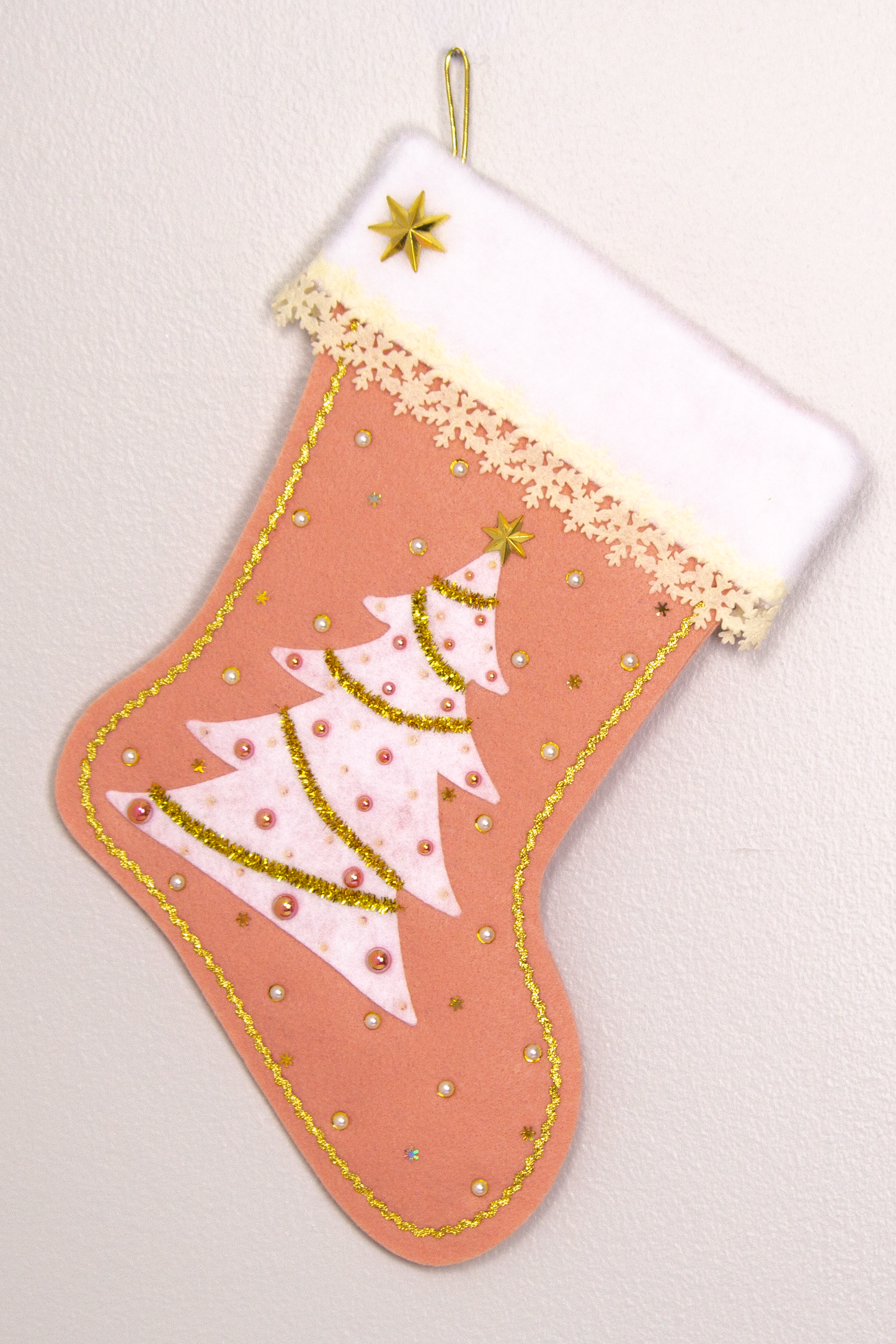 White felt tree on coral felt handmade Christmas tree with delicate laser cut felt trim, plastic star buttons, tinsel pipe cleaner, tiny snowflake sequins and decorated in cream, white, coral & gold. (front of Tree stocking)