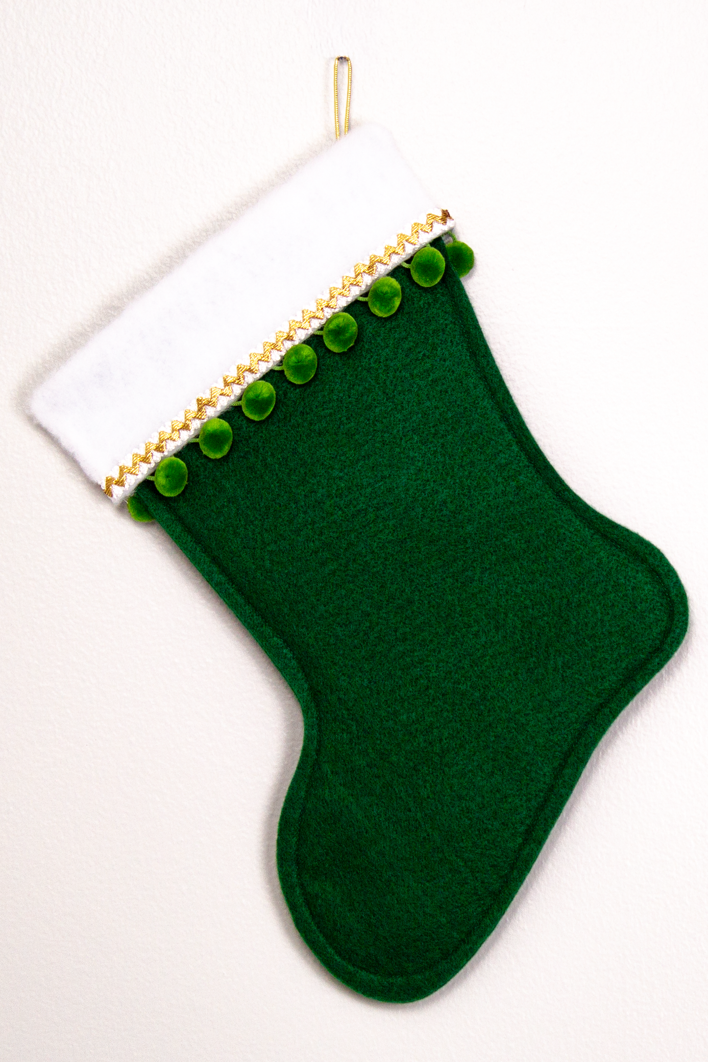 Dark green felt handmade Christmas stocking with pom poms and decorated in gold and green. (back of Whippet dog stocking)