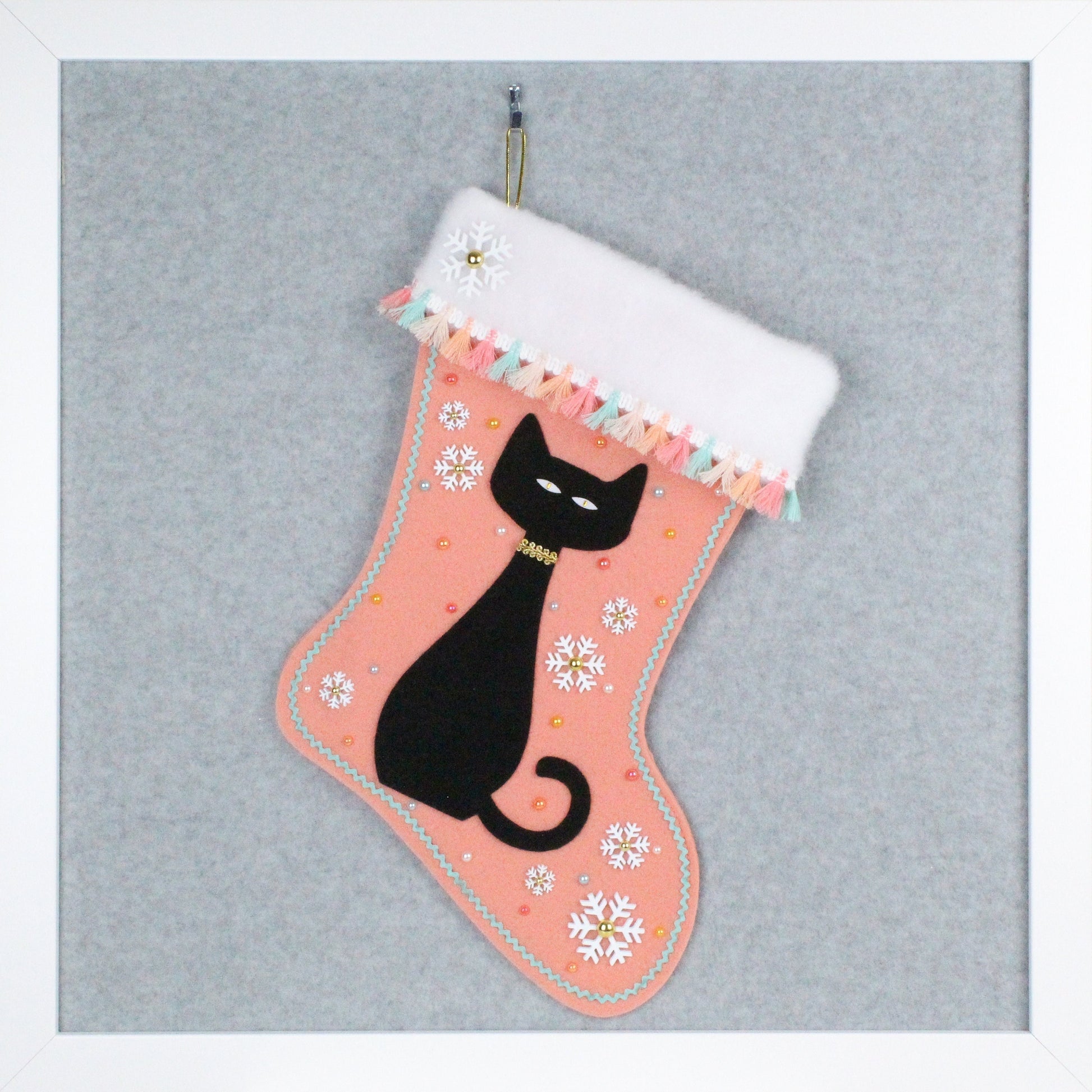 Black cat on coral felt OOAK handmade Christmas stocking with white snowflakes, pastel multicolored tassel fringe, and gold decorations.